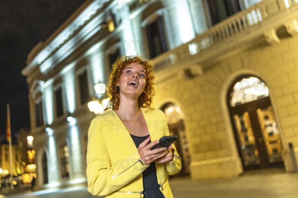 Caucasian modern and casual happy woman using phone while exploring downtown at night
