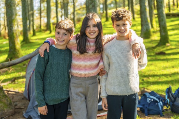 Portrait of three kids of same family embracing from the back in the forest