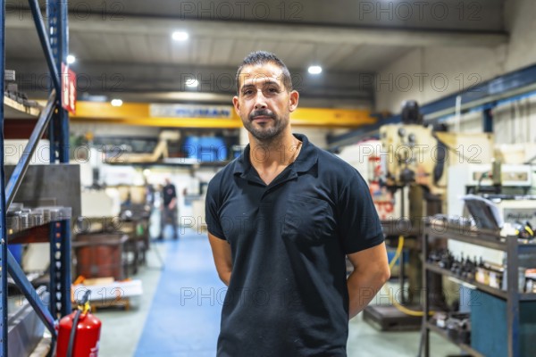 Portrait of a caucasian adult manual worker standing with hands on back looking proud in the factory