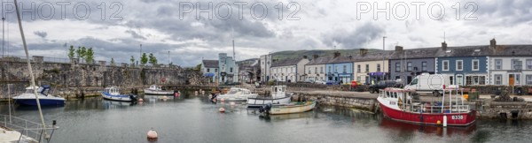Small harbour with boats and surrounding buildings under a grey sky, Ballycastle