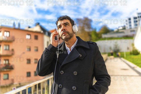 Casual mature handsome businessman listening to music walking along the city