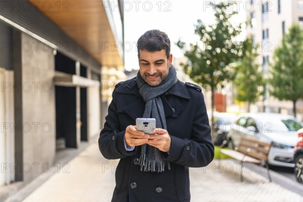 Elegant caucasian man with winter clothes using phone walking along the city