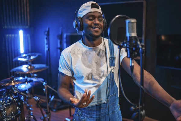 Young, happy african american male artist singing passionately in a professional music recording studio, surrounded by modern equipment and vibrant energy