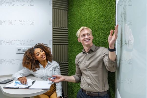 Two managers analyzing data and discussing strategy during a meeting in a modern coworking office with a green wall