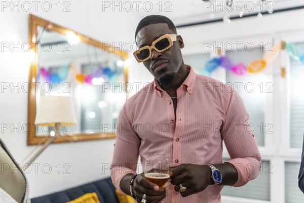 Cool handsome african man wearing sunglasses in a house party drinking beer
