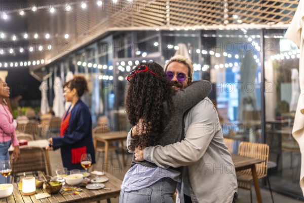 Meeting between multi-ethnic friends embracing in a terrace of a night bar