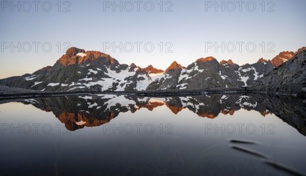 Rocky mountain peaks reflected in a small pond, mountain landscape with alpenglow at sunrise, at the Trollfjord Hytta, at the Trollfjord, Lofoten and Vesterålen, Nordland, Norway, Europe