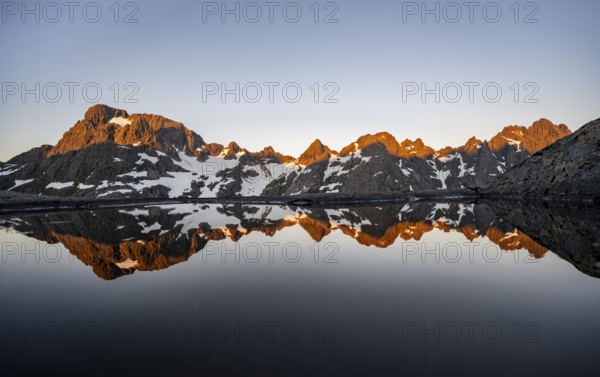 Rocky mountain peaks reflected in a small pond, mountain landscape with alpenglow at sunrise, at the Trollfjord Hytta, at the Trollfjord, Lofoten and Vesterålen, Nordland, Norway, Europe