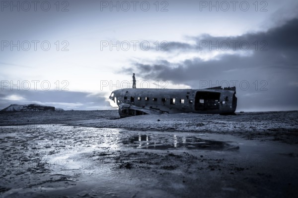 A man on the crashed military plane in Solheimasandur in winter with the frozen ground