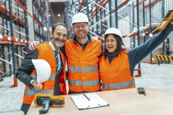Warehouse workers and their manager are hugging each other, celebrating a successful logistics operation in a large distribution center