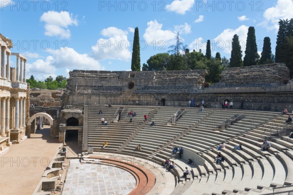 An ancient amphitheatre with stone seats under a blue sky with clouds and trees in the background, Teatro Romano de Mérida, Roman theatre of Merida, Merida, Badajoz, Extremadura, Spain, UNESCO World Heritage Site, Europe