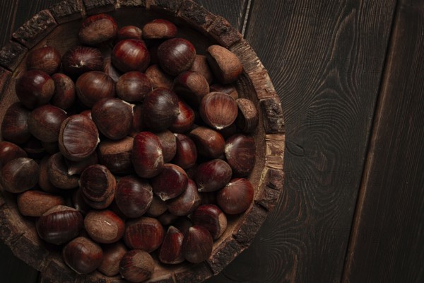 Fresh chestnuts, in a wooden bowl, top view, no people
