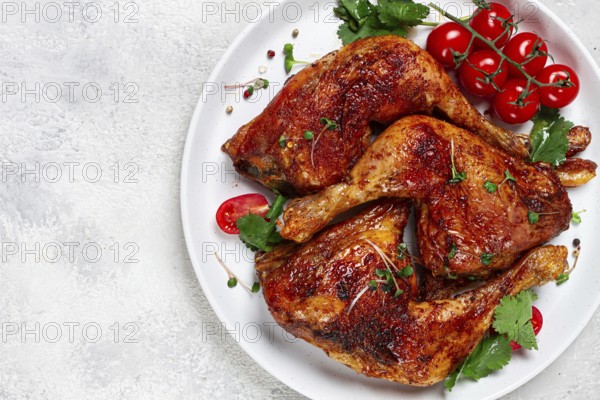 Grilled fried chicken legs, served, with fresh cherry tomatoes, and herbs, on a white plate, homemade, no people