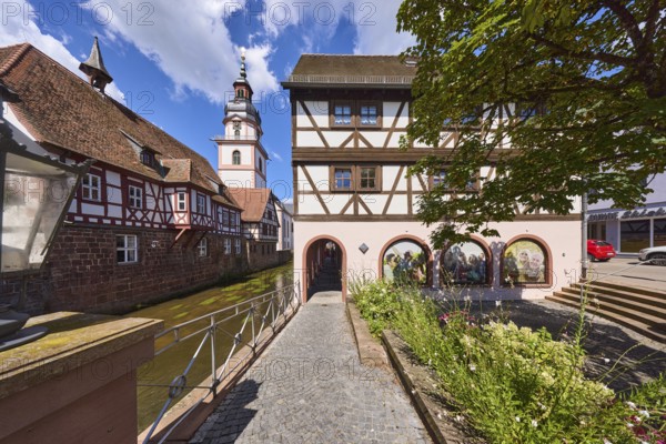 River Mümling, half-timbered houses, archway, church tower, lantern, metal railing, flower bed, blue sky with cumulus clouds, main street, Erbach, Odenwald, Odenwaldkreis, Hesse, Germany, Europe