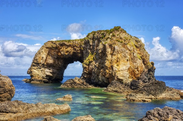 Striking rock formation with arch by the sea under a blue sky and clouds, Great Pollet Sea Arch