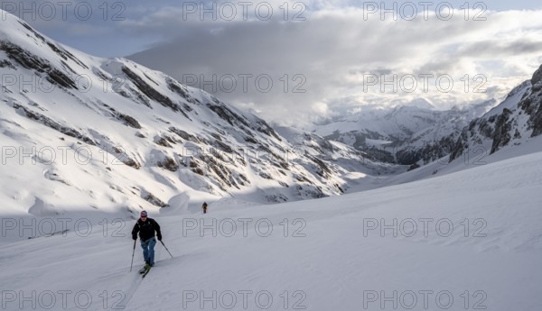 Ski tourers in a snowy mountain landscape in the morning light, view into the Iffigtal, cloudy mood, high tour, Bernese Alps, Bernese Oberland, Switzerland, Europe