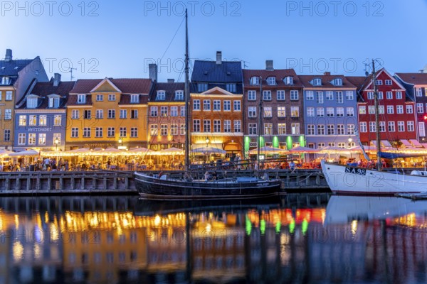Colourful houses, restaurants and historic ships on the Nyhavn canal and harbour at dusk, Copenhagen, Denmark, Europe
