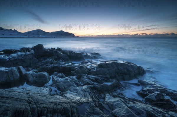 Long exposure after sunset, winter at Skagsanden, rocks washed over by the sea on the beach at Flakstad, Flakstadøy, Lofoten, Nordland, Norway, Europe