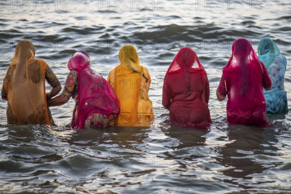 Hindu pilgrims, woman in colourful saris, take a holy dip in the sea in front of sunrise at Ghat Agni Theertham, Rameswaram or Rameshwaram, Pamban Island, Tamil Nadu, India, Asia