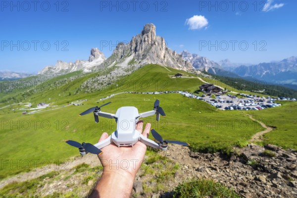Hand holding a drone ready to fly over passo giau in the italian dolomites, showcasing the breathtaking mountain landscape on a sunny summer day