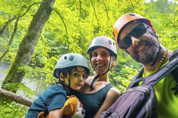 Happy family taking selfie while hiking and wearing helmets in the beautiful vintgar gorge near bled, slovenia