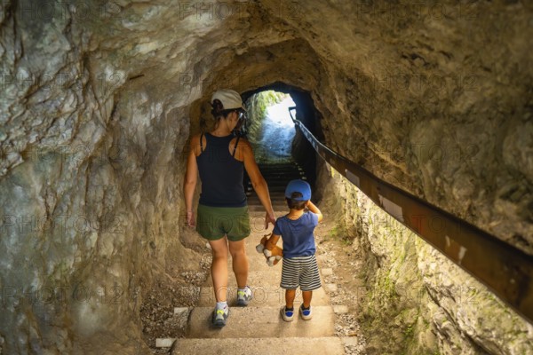 Mother and son walking through a tunnel in tolmin gorge, a popular tourist destination in slovenia