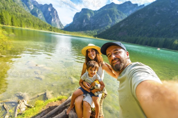 Happy family enjoying summer vacation taking a selfie at lake dobbiaco with the dolomites in the background