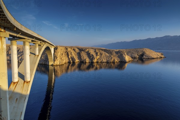 Pag bridge stretches across a lake to a rocky island at sunrise, Pag, Croatia, Europe