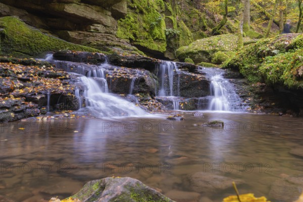 Small waterfall in a moss-covered forest with autumn leaves, Monbachtal, Bad Liebenzell, district of Calw, Black Forest, Germany, Europe