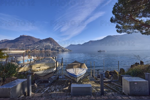 Motorboats, lake, hilly landscape with village, haze, blue sky with cirrostratus clouds, Lake Lugano, Lugano, Lugano district, Ticino, Switzerland, Europe