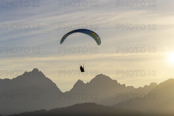 Paraglider hovering over a mountain silhouette at dusk, Schwangau, Ostallgäu, Allgäu, Swabia, Bavaria, Germany, Europe