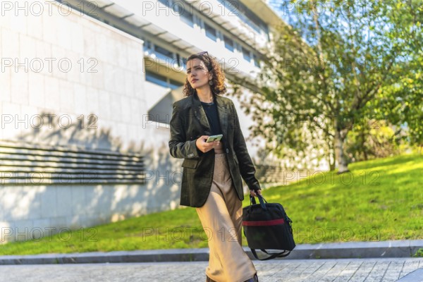 Horizontal photo with copy space of a modern arab businesswoman using mobile walking along the city