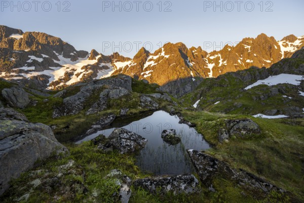 Rocky mountain peaks with reflection, small pond in moor landscape at Trollfjord Hytta, mountain landscape with alpenglow at sunrise, at Trollfjord, Lofoten and Vesterålen, Nordland, Norway, Europe