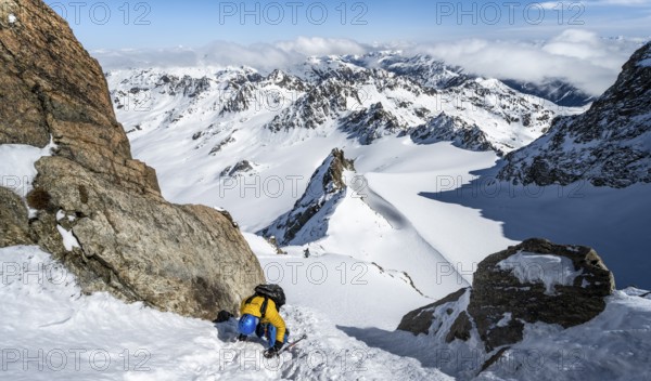Mountaineer with ice axe and crampons, ascent through steep snowfield to Piz Kesch or Piz d'Es-cha in winter, view of mountain panorama with Vadret da Porchabella glacier, Albula Alps, Rhaetian Alps, Grisons, Eastern Switzerland, Switzerland, Europe