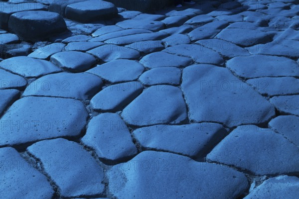 Close-up of large grey smooth and worn lava stones in a street at the ancient ruins of Pompeii, Campania region, Italy, Europe