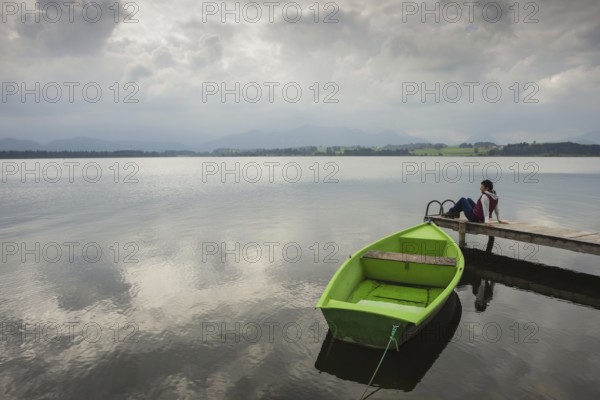 Woman 50-60, wooden jetty, green rowing boat, Hopfensee, Hopfen am See, near Füssen, Ostallgäu, Allgäu, Bavaria, Germany, Europe