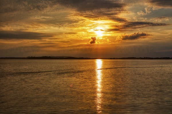 A bright orange sunset is reflected on the surface of the water, Übersee, Chiemsee