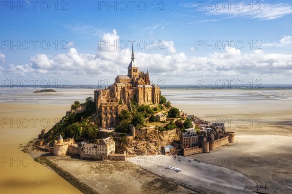 High-lying abbey on a rocky island, surrounded by sand and blue sky, Le Mont-Saint-Michel