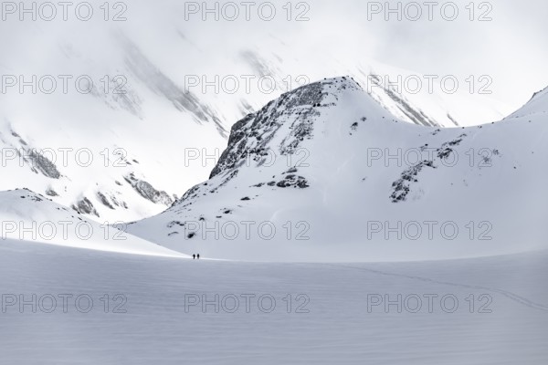Dramatic atmosphere, Ski tourers in the vast landscape, Snow-covered mountain landscape, Bernese Alps, Bernese Oberland, Switzerland, Europe