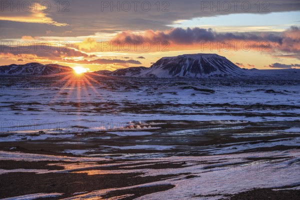Hot springs and geothermal area in front of mountain landscape in winter, sunbeams, cloudy mood, Hverir, Namafjall, Myvatn, Iceland, Europe