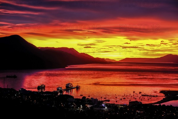 Ushuaia, Tierra del Fuego, Argentina, Glowing red sunrise over the Beagle Channel, the Beagle Channel is a natural waterway at the southern tip of South America that connects the Atlantic Ocean with the Pacific Ocean. Ushuaia is the southernmost city in the world, the end of the world. Behind mountain range on the island of Navarino in Chile, Dientes de Navarino, South America
