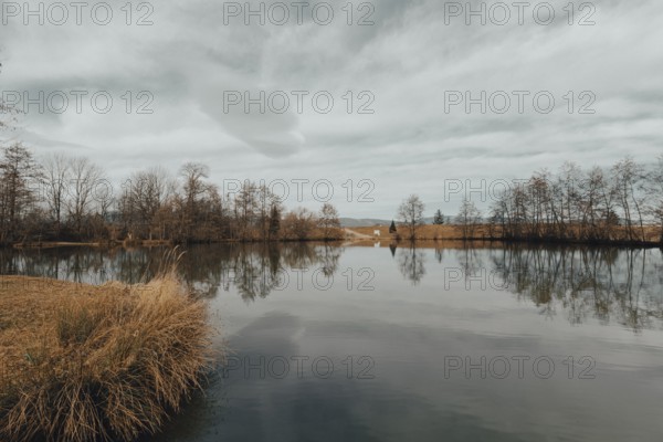 Tranquil pond with reflection of trees and clouds, surrounded by a natural landscape, Drudenteich, Neunkirchen, Lower Austria, Austria, Europe