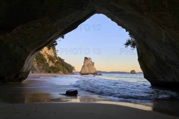 Cave opening shows a calm sea scene with rock formations in the twilight, Cathedral Cove, Coromandel, Canterbury, North Island, New Zealand, Oceania