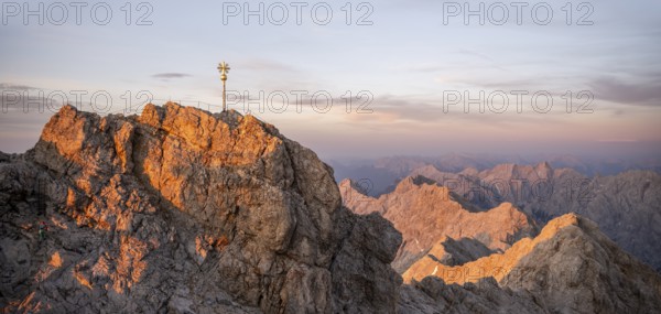 Summit of the Zugspitze with golden summit cross, alpenglow at sunset, Northern Limestone Alps, Wetterstein Mountains, Bavaria, Germany, Europe