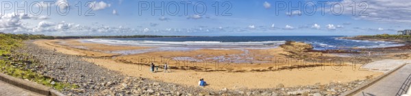 Wide coastal landscape with sandy beach and rocks under a blue sky and clouds, Lahinch Beach