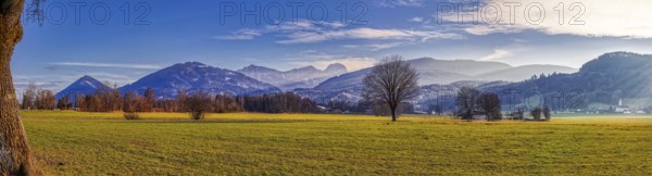 Wide green meadow in front of a mountain backdrop under a blue sky with light clouds, Bad Feilnbach