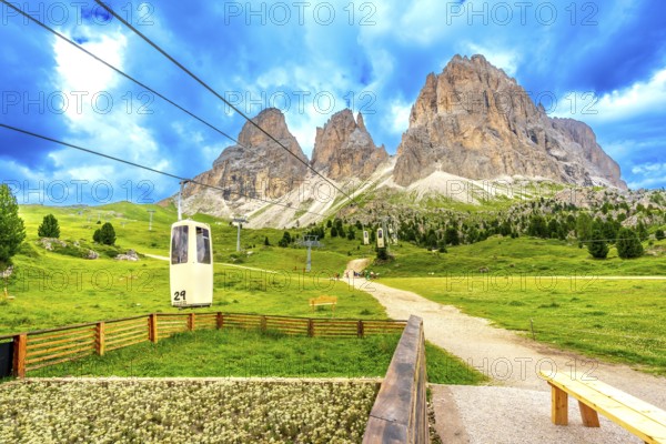 Cable car ascending to the sassolungo group, with its majestic peaks, located in the italian dolomites during a vibrant summer day