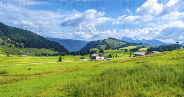 Breathtaking summer scenery in alpe di siusi, dolomites, italy, showcasing lush green meadows, rolling hills, traditional houses, and a vibrant blue sky