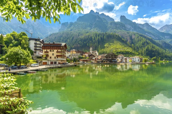 Tranquil summer scene of alleghe village reflecting on the emerald waters of lake alleghe, nestled amidst the stunning dolomites mountains in italy