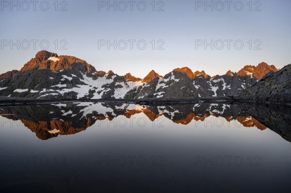 Rocky mountain peaks reflected in a small pond, mountain landscape with alpenglow at sunrise, at the Trollfjord Hytta, at the Trollfjord, Lofoten and Vesterålen, Nordland, Norway, Europe